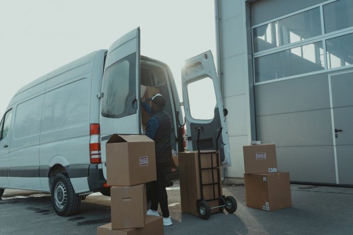 A deliveryman loading courier boxes into a van.