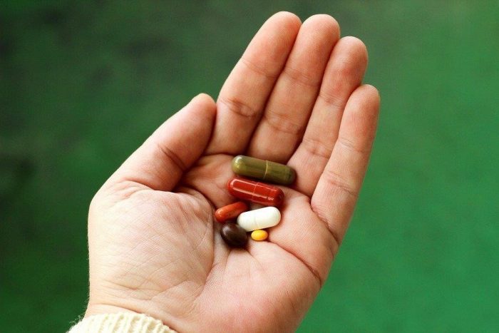 A person holding different pills and tablets